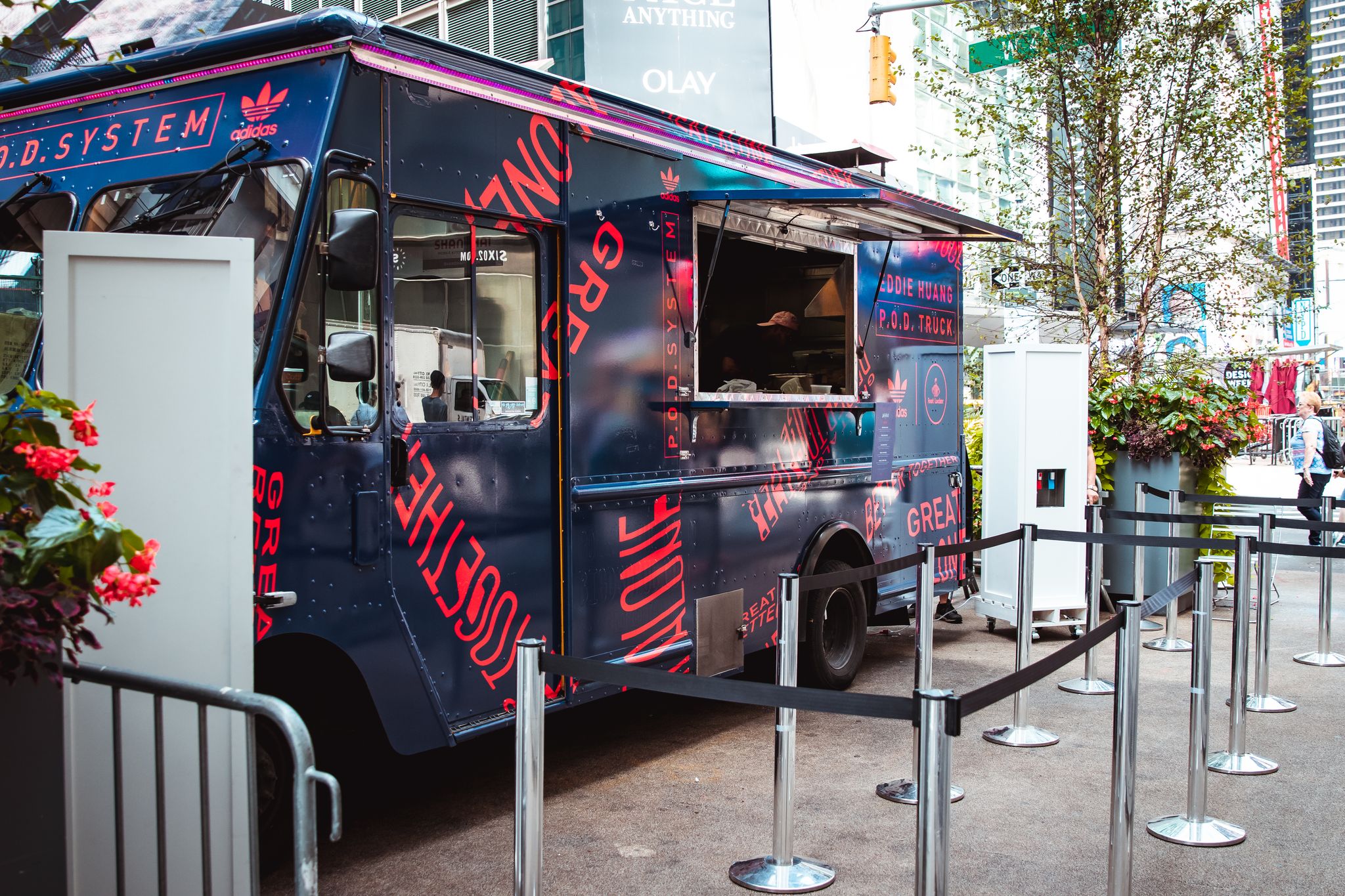 Navy blue food truck with red and white lettering parked on sidewalk, serving window open.