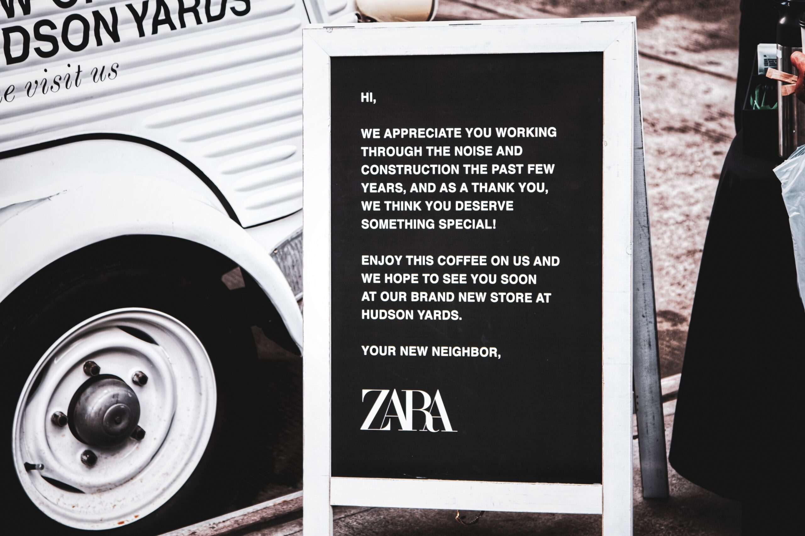 Zara sandwich board thanks visitors for patience during construction, offers free coffee nearby.