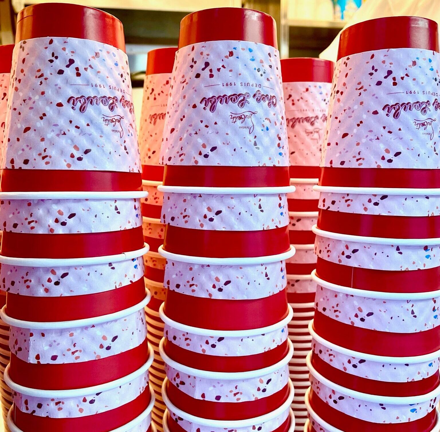 Red and white speckled ice cream cups are stacked in neat rows at a mobile pop-up display.