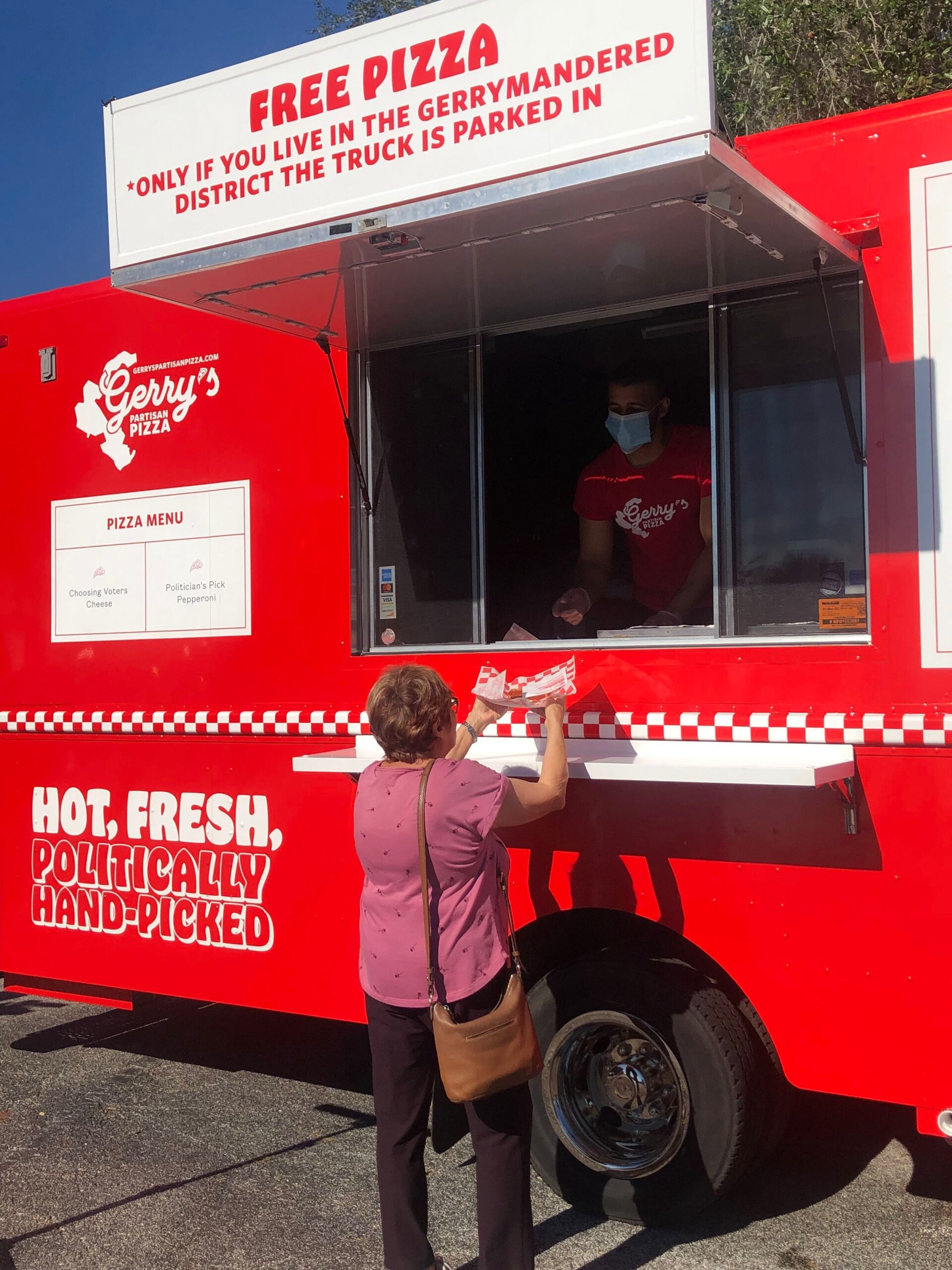 A woman gets pizza from Gerry's Pizza truck, free only for local district residents.