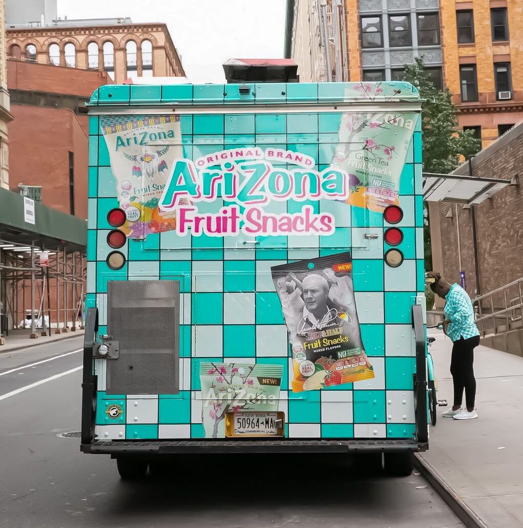 Arizona Fruit Snacks truck with teal checkered back, parked on city street; person stands nearby.