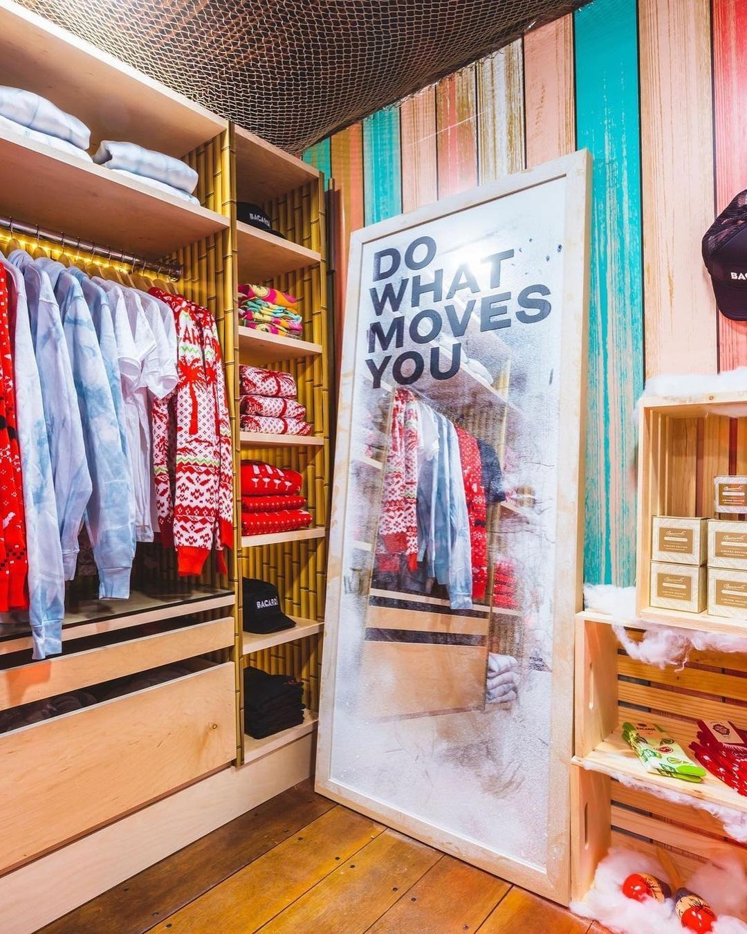 Holiday pop-up shop with sweaters, shirts, hats, and a mirror reading DO WHAT MOVES YOU.