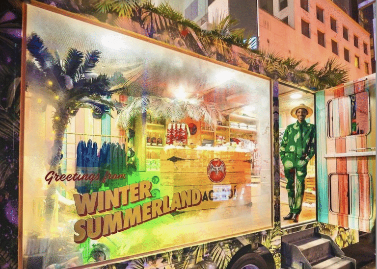 Holiday pop-up truck with tropical plants, mural, snacks, drinks, and a man in a green suit.