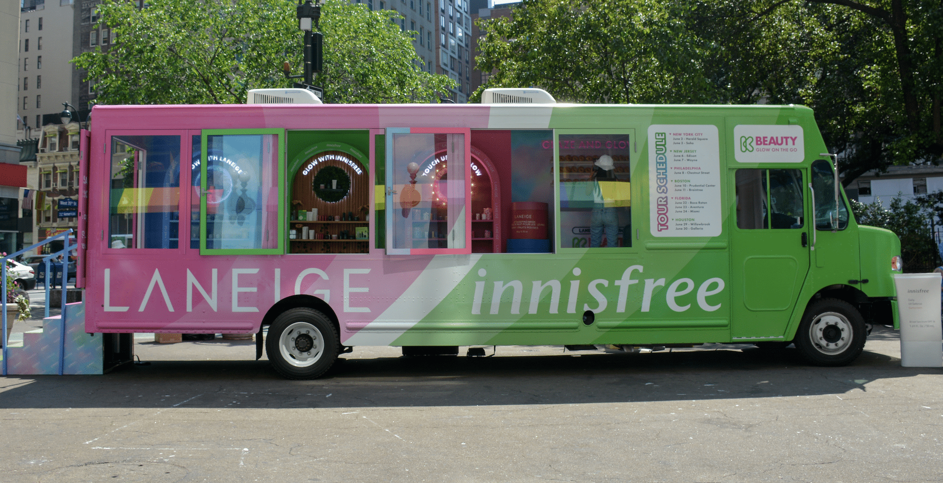 Glass box truck with LANEIGE on pink and innisfree on green, parked on a city street.