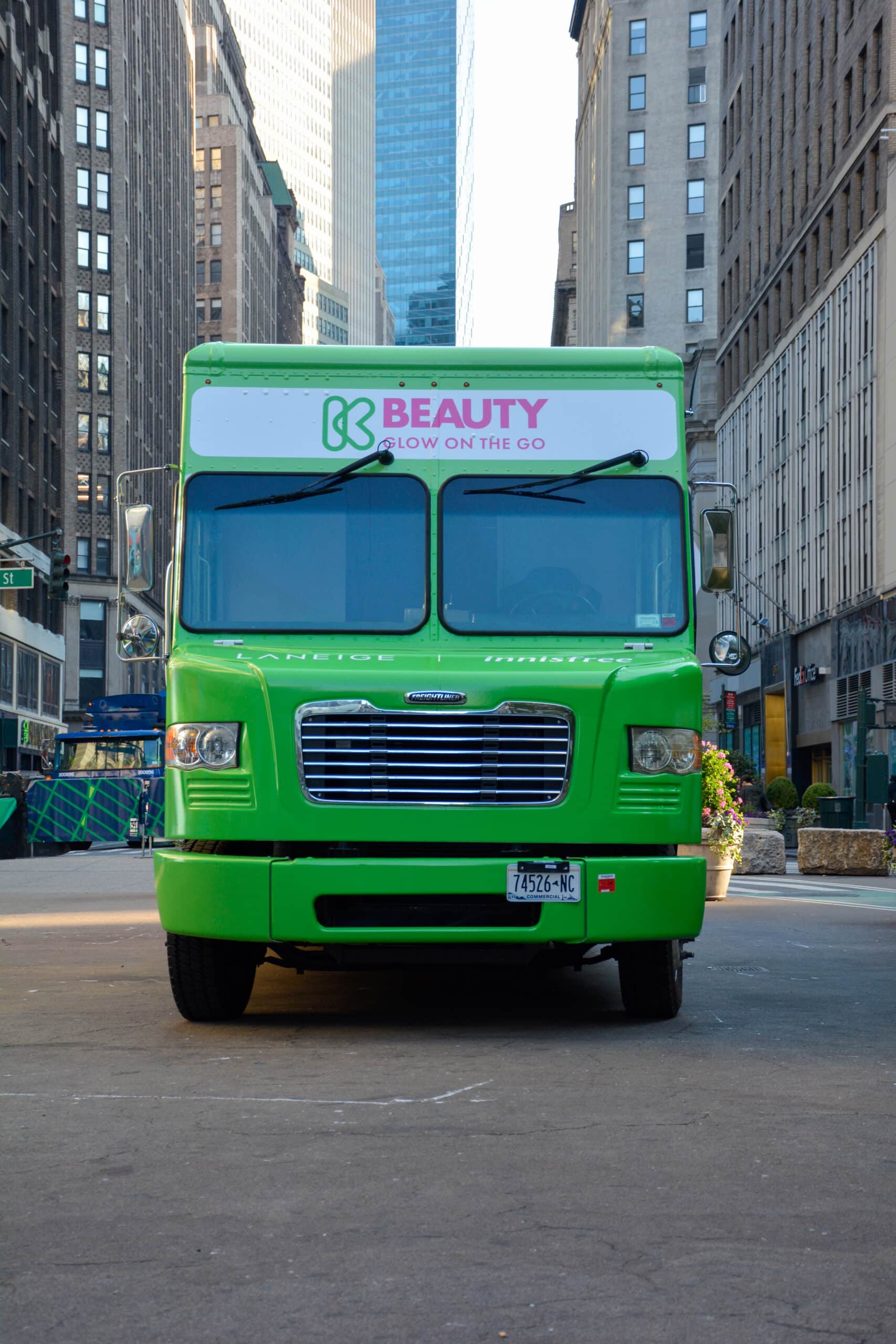 Green Glass Box beauty truck with "BEAUTY BLOW ON THE GO" parked on city street.