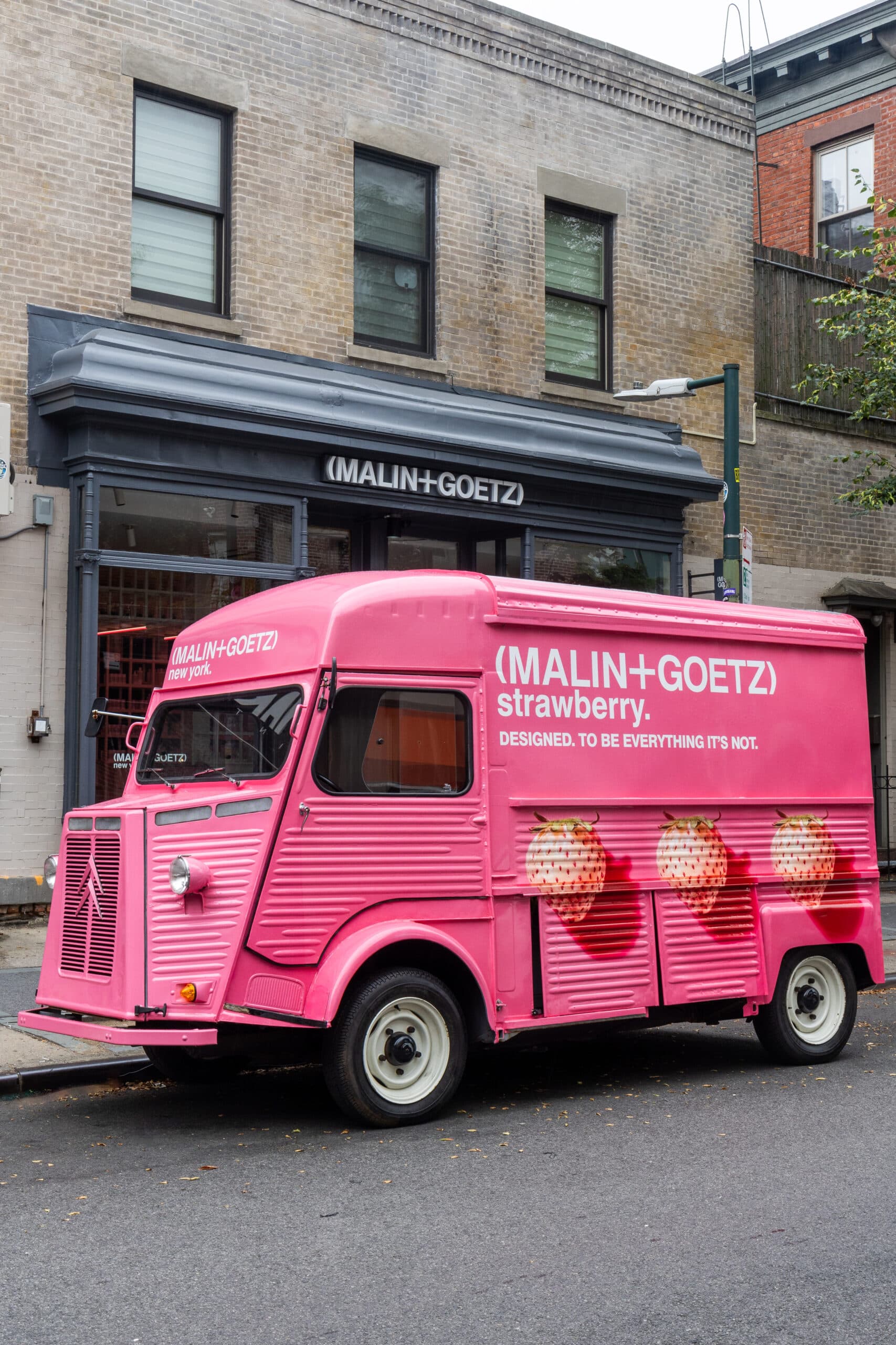 Pink MALIN+GOETZ strawberry van with strawberry images parked outside its matching storefront.
