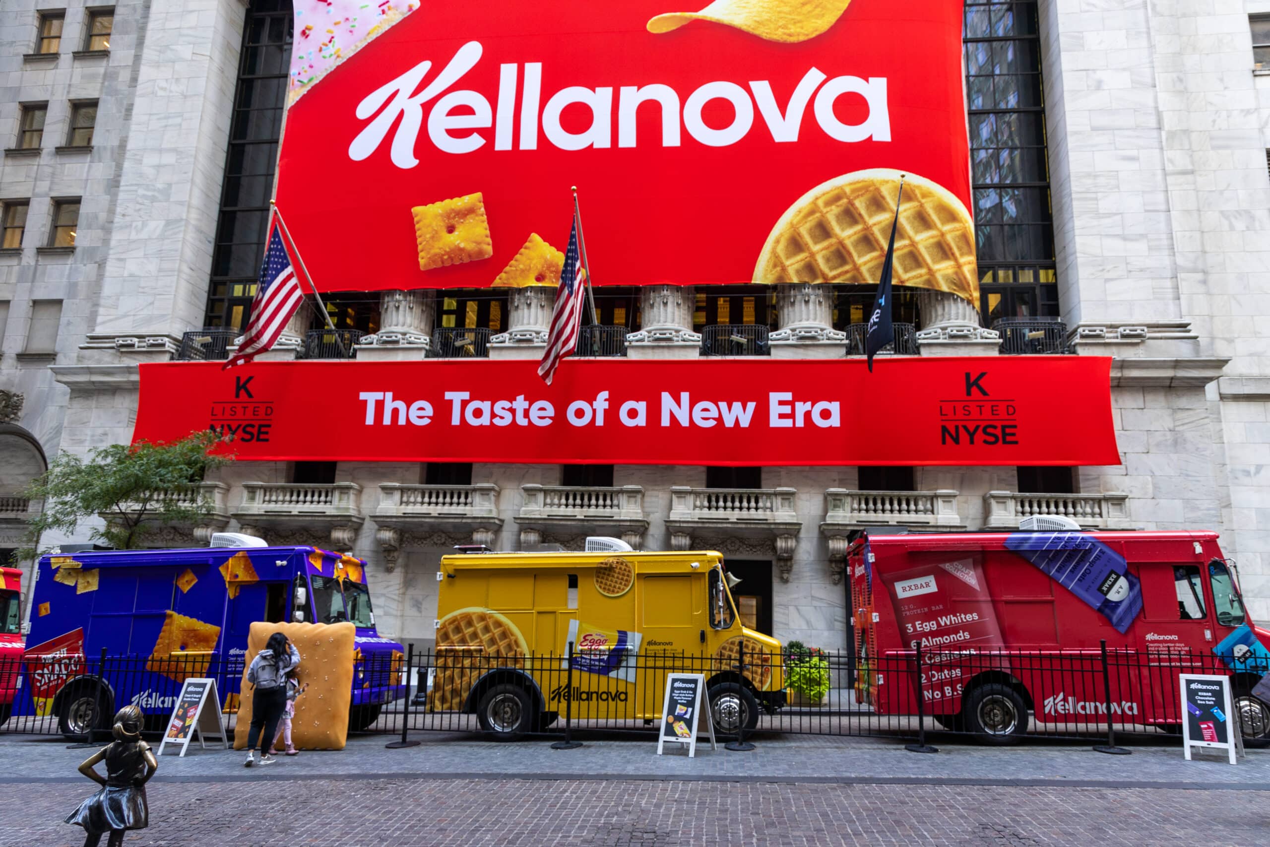 Kellanova food trucks and banner outside the New York Stock Exchange with two American flags.