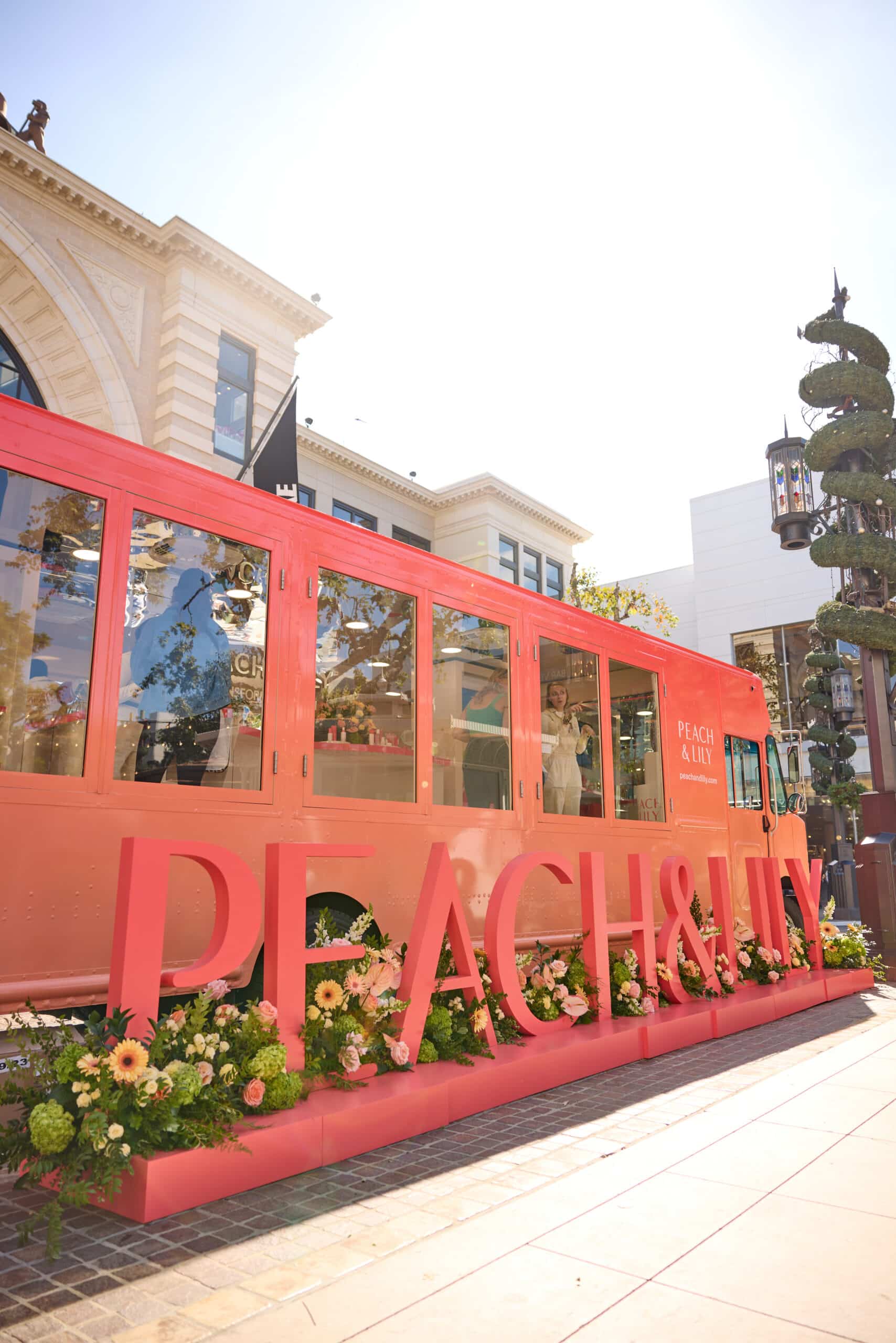 Pink Glass Box Truck with PEACH & LILY letters, flower decorations, parked outdoors.