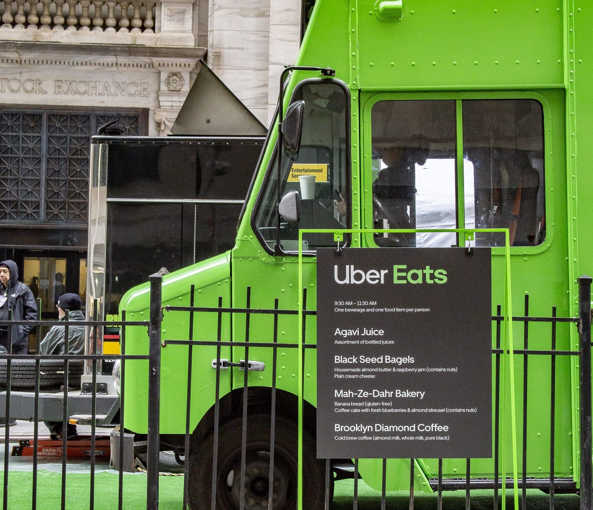 Uber Eats green food truck parked on street with menu listing Agavi Juice, Bagels, Bakery, Coffee.