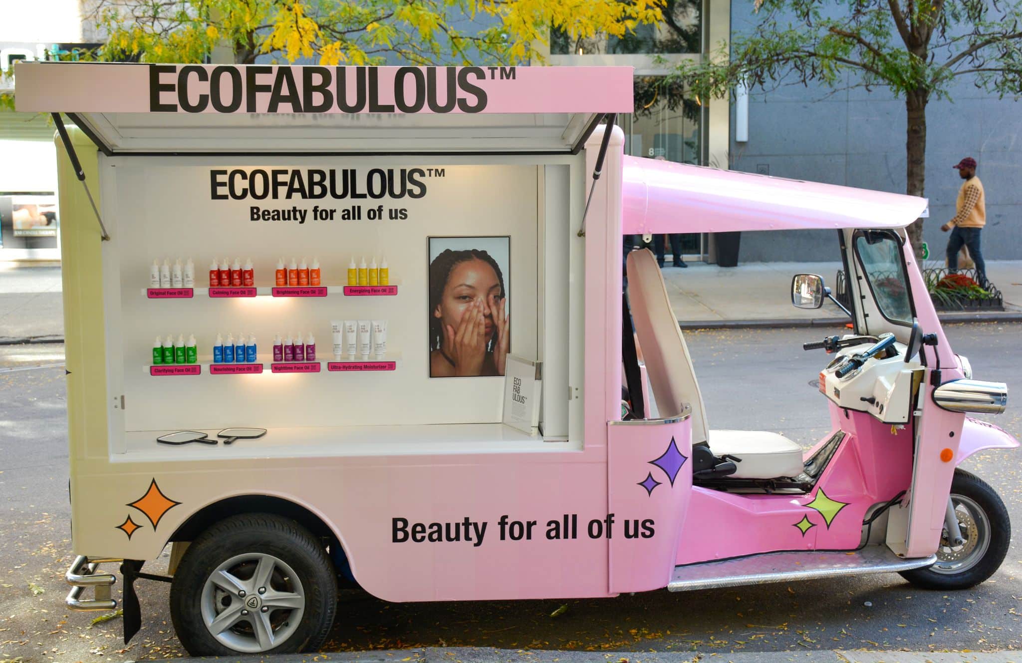 Pink Ecofabulous beauty truck parked on city street with skincare products and slogan displayed.
