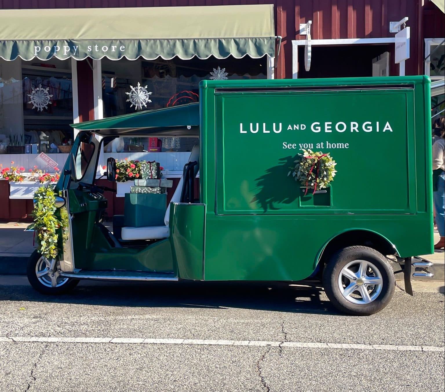 Green Tuk Tuk with flowers and &ldquo;Lulu and Georgia, See you at home&rdquo; parked by shops.