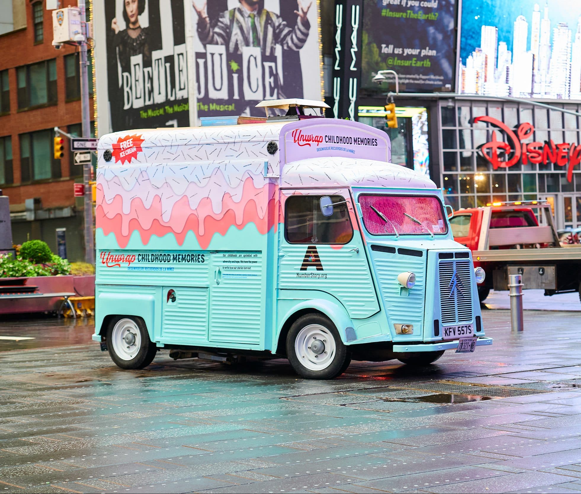 Pastel blue and pink vintage Citroens ice cream truck parked on wet city street.