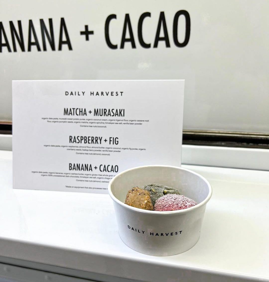 Daily Harvest cup with three bites sits before a menu listing Matcha, Raspberry, and Banana flavors.