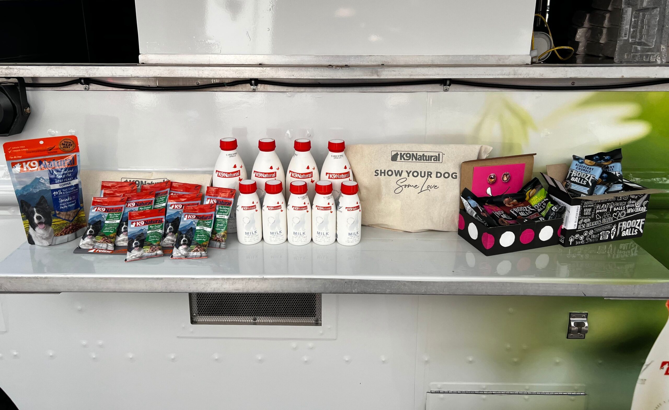 Pet treats, shampoo bottles, tote bag, waste bags, and dispenser on a white counter.