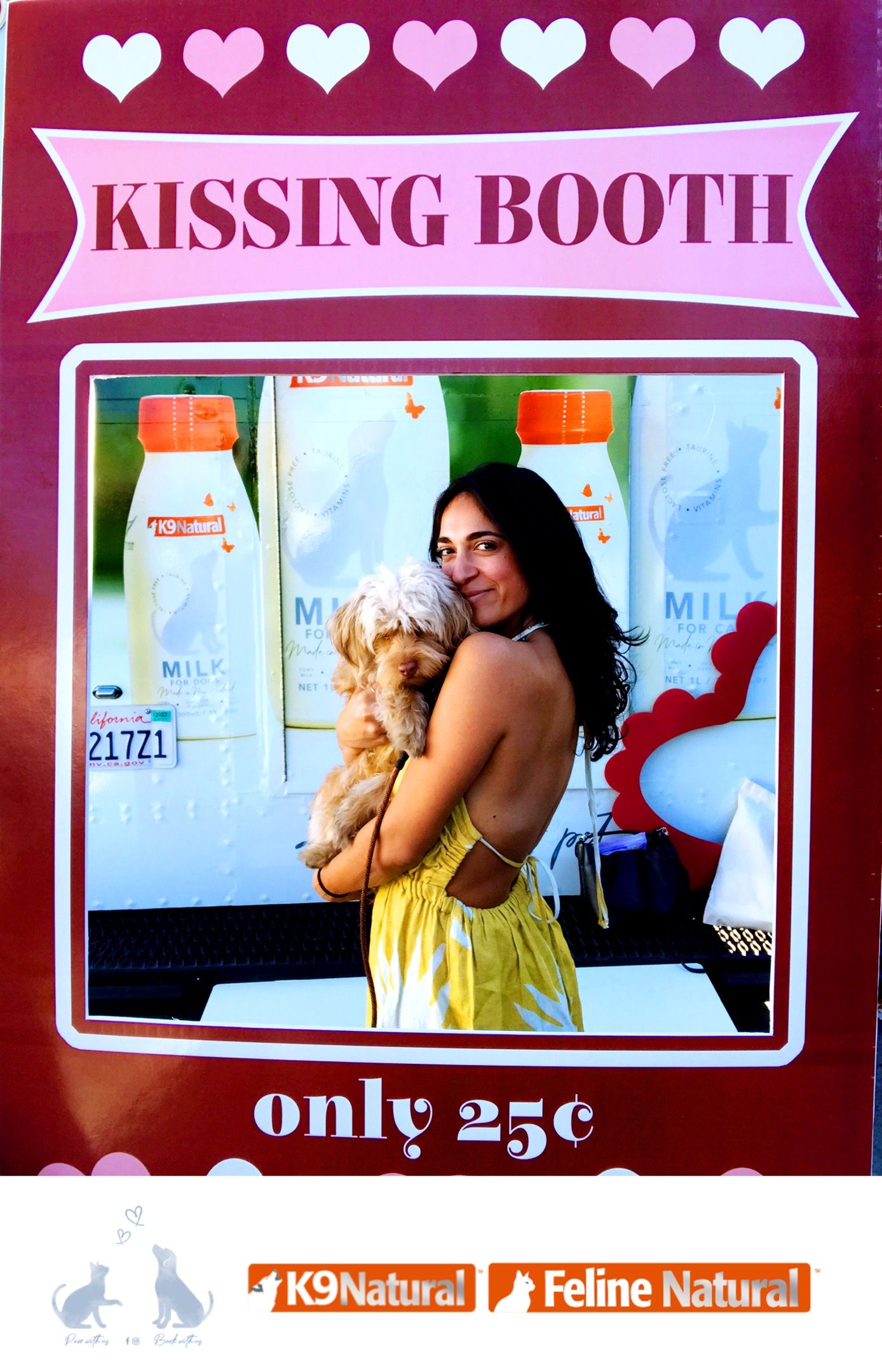 Woman in yellow dress hugs and kisses small dog at a Kissing Booth with pet product logos.