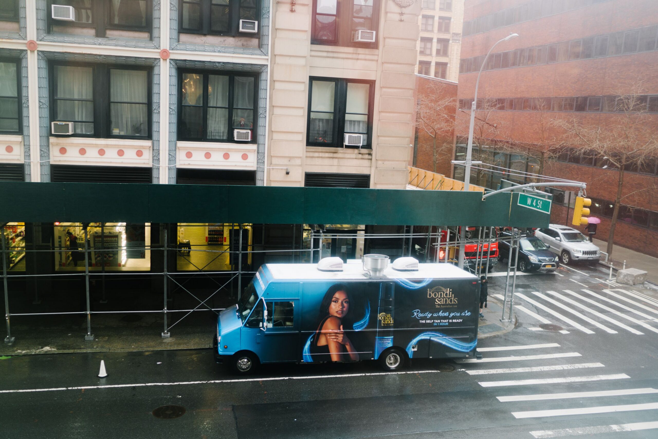 Blue food truck with "bond sweets" branding serves treats on a city street near scaffolding.