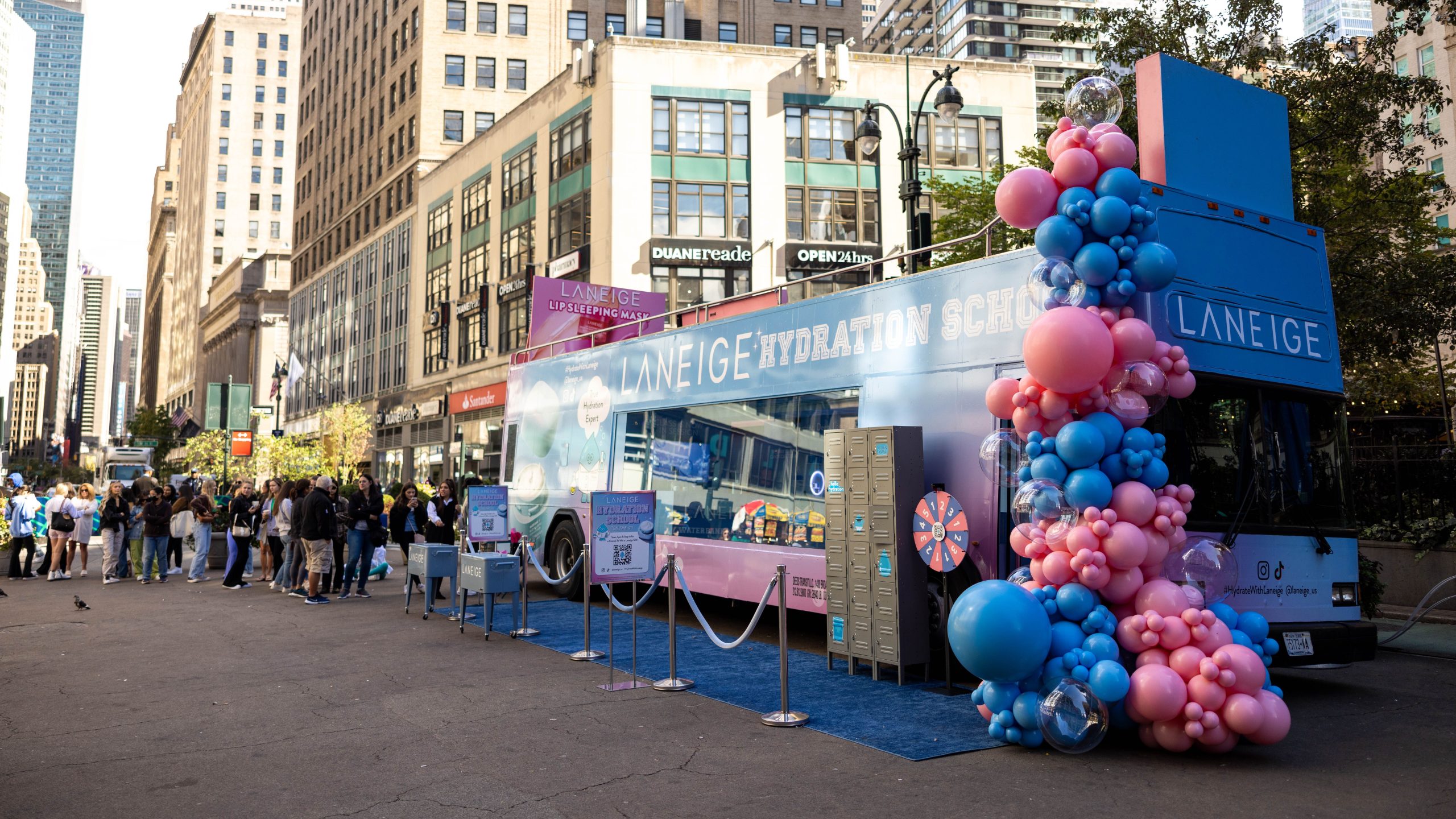 Laneige pop-up bus with balloons and a prize wheel; people line up on a city street.