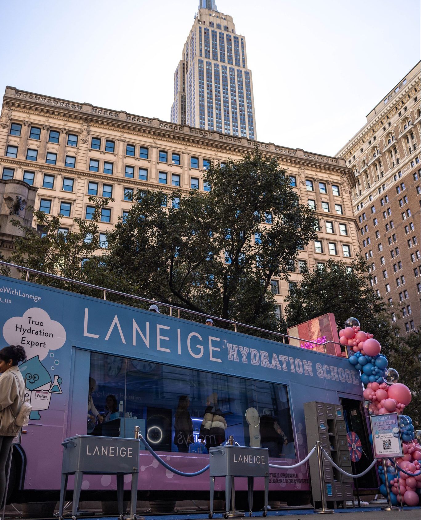 Laneige pop-up with balloons in front of city buildings; people explore inside, branding visible.