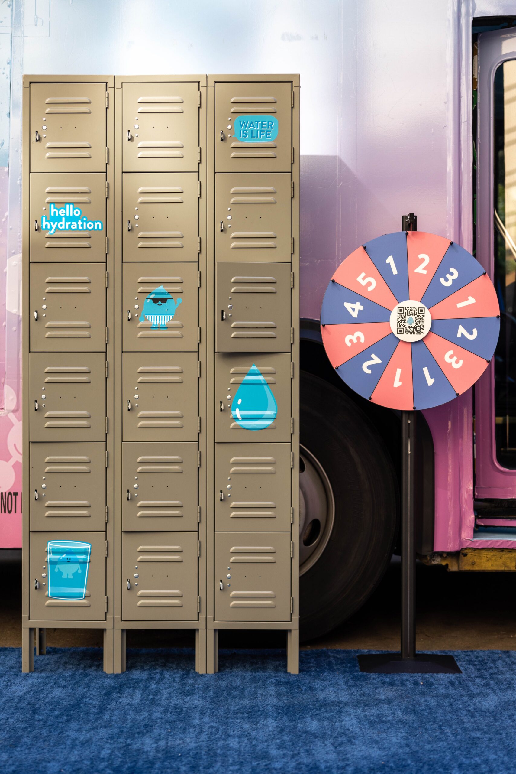 Beige lockers with blue stickers beside a red and blue prize wheel at a Laneige pop up event.