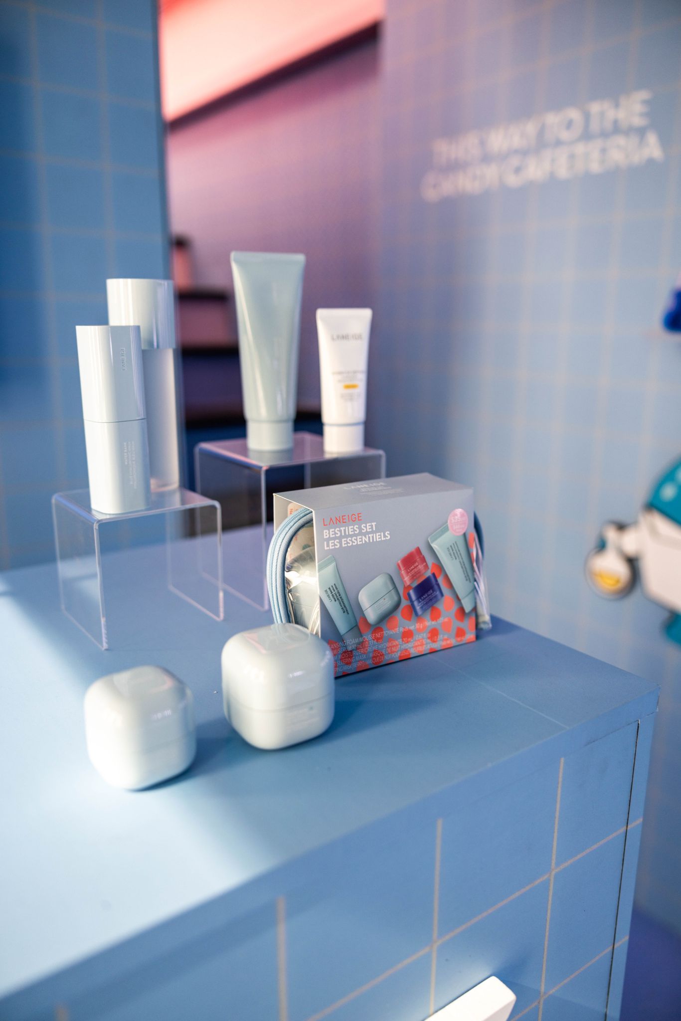 Laneige skincare bottles, tubes, and jars on a blue counter with a Besties Set gift box in front.