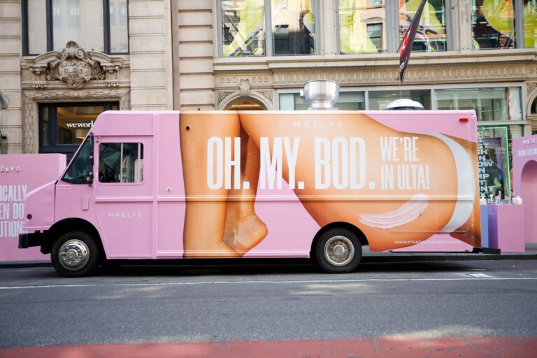 Pink truck promoting House of Bod pop up parked on city street, advertisement visible on side.