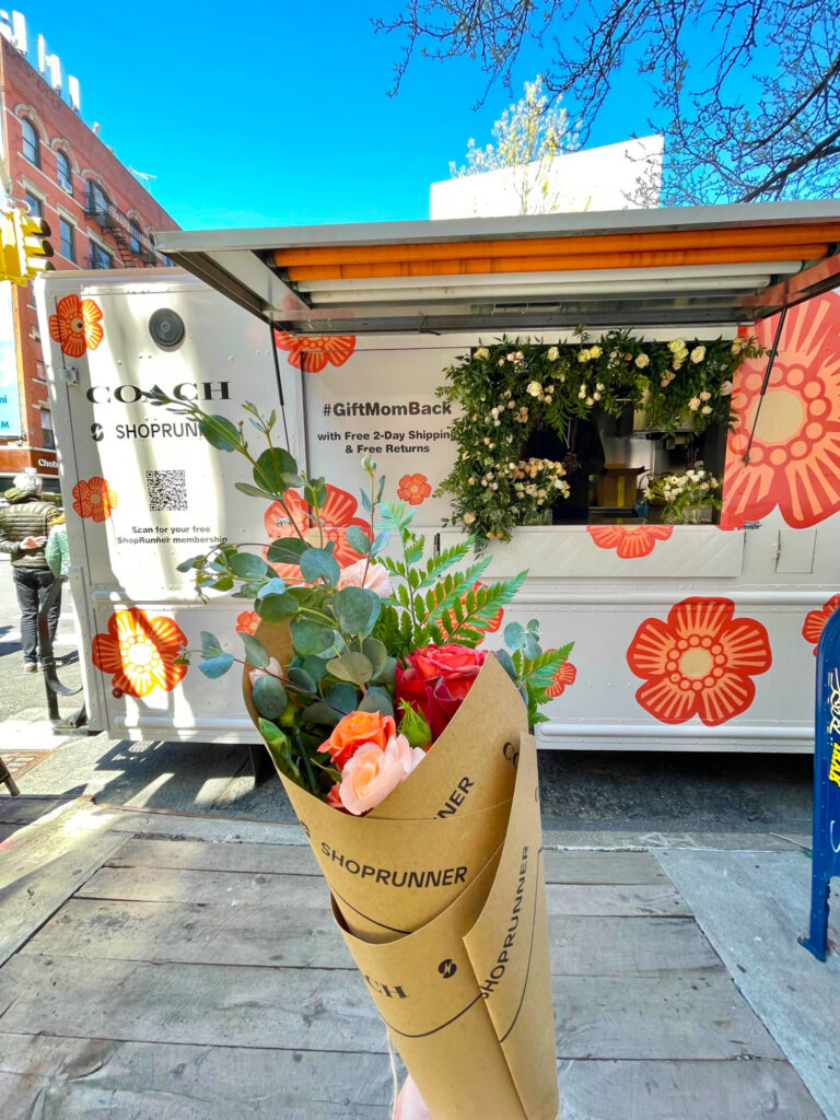 Bouquet of roses held in front of a COACH and SHOPRUNNER flower-decorated food truck.
