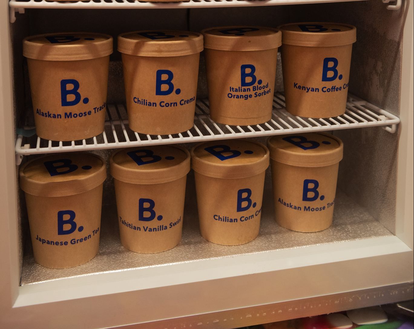 Brown ice cream tubs with blue B. logos and flavors like Moose Track and Green Tea on shelves.