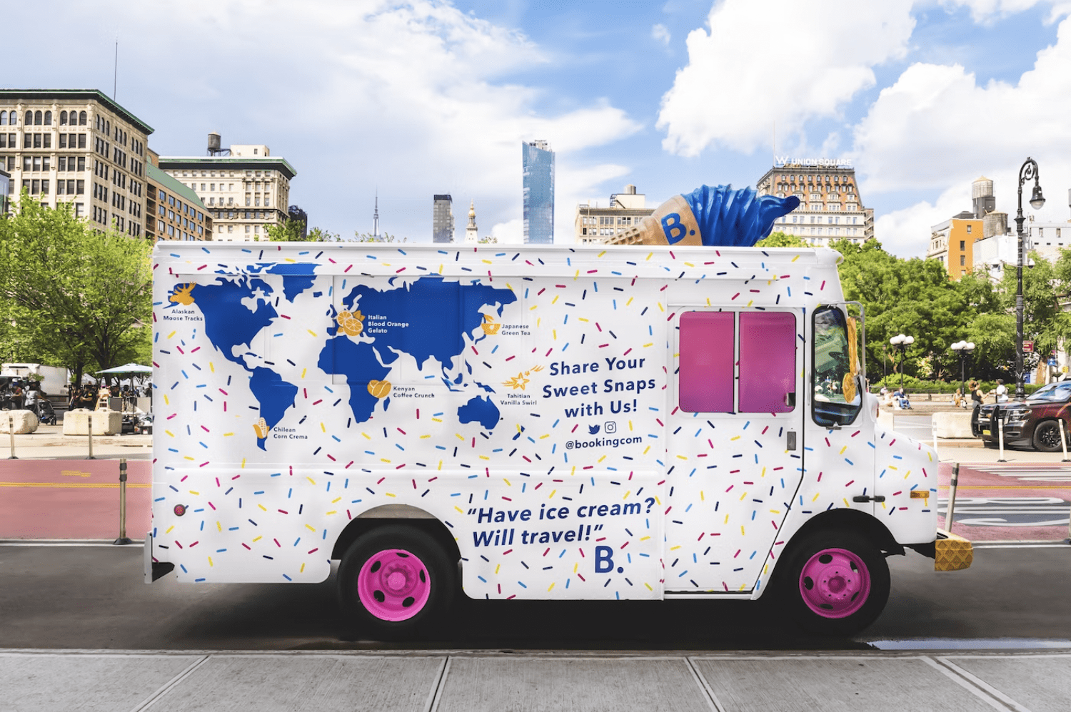 Booking.com ice cream truck with pink wheels, sprinkles, and a world map parked on city street.