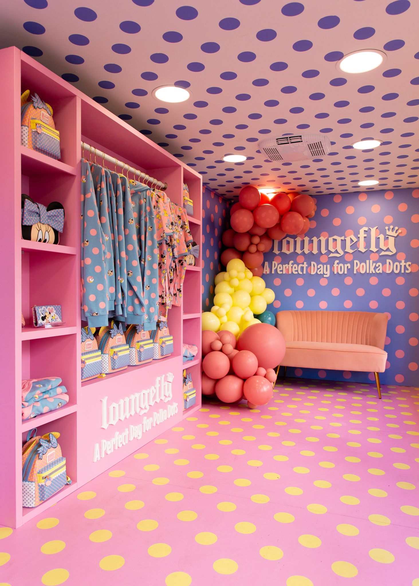 Pink shelves with polka dot bags and robes, balloon-decorated pink sofa, polka dots everywhere.
