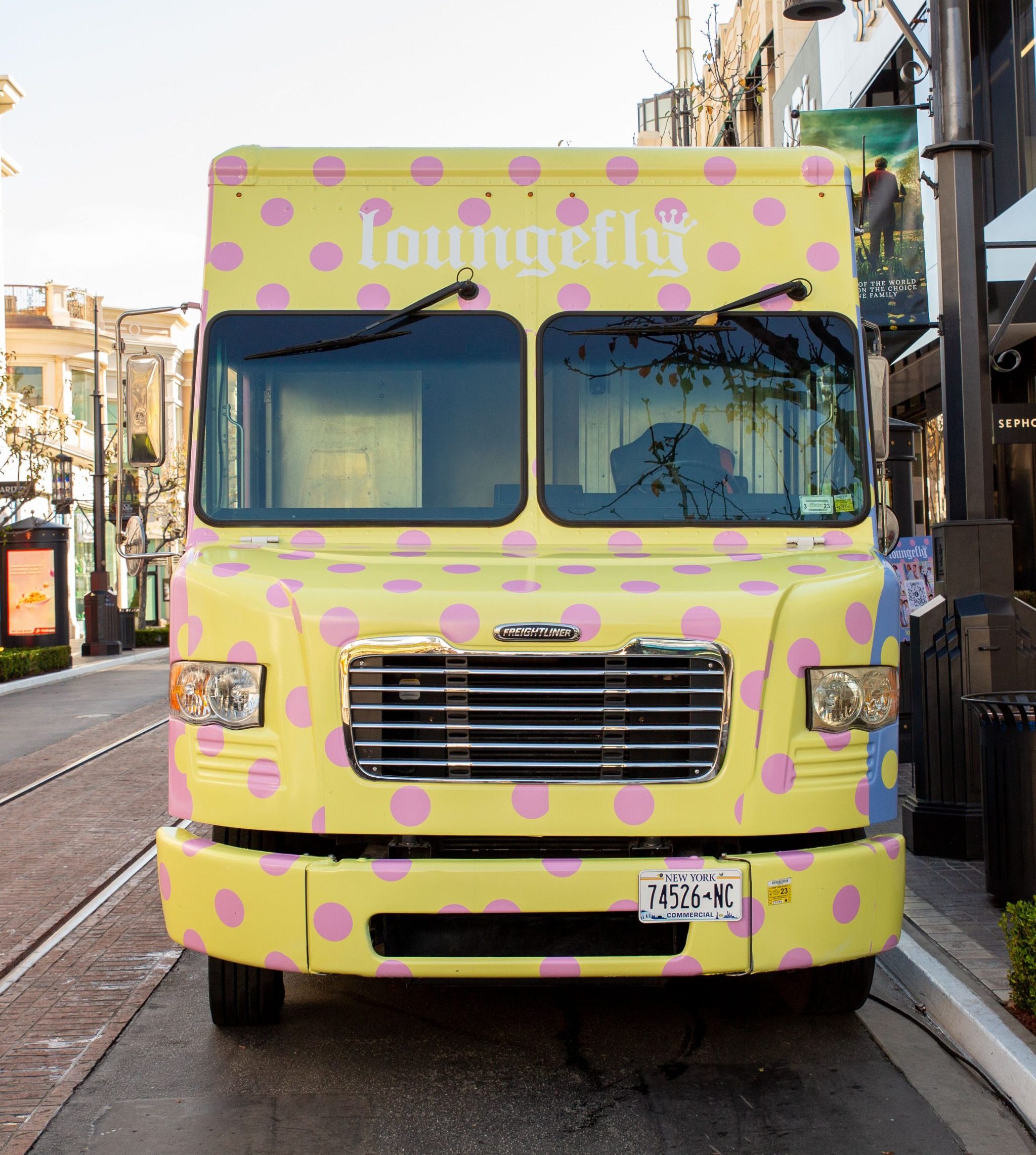 Yellow polka dot Loungefly truck with pink spots parked on city street, logo on front.