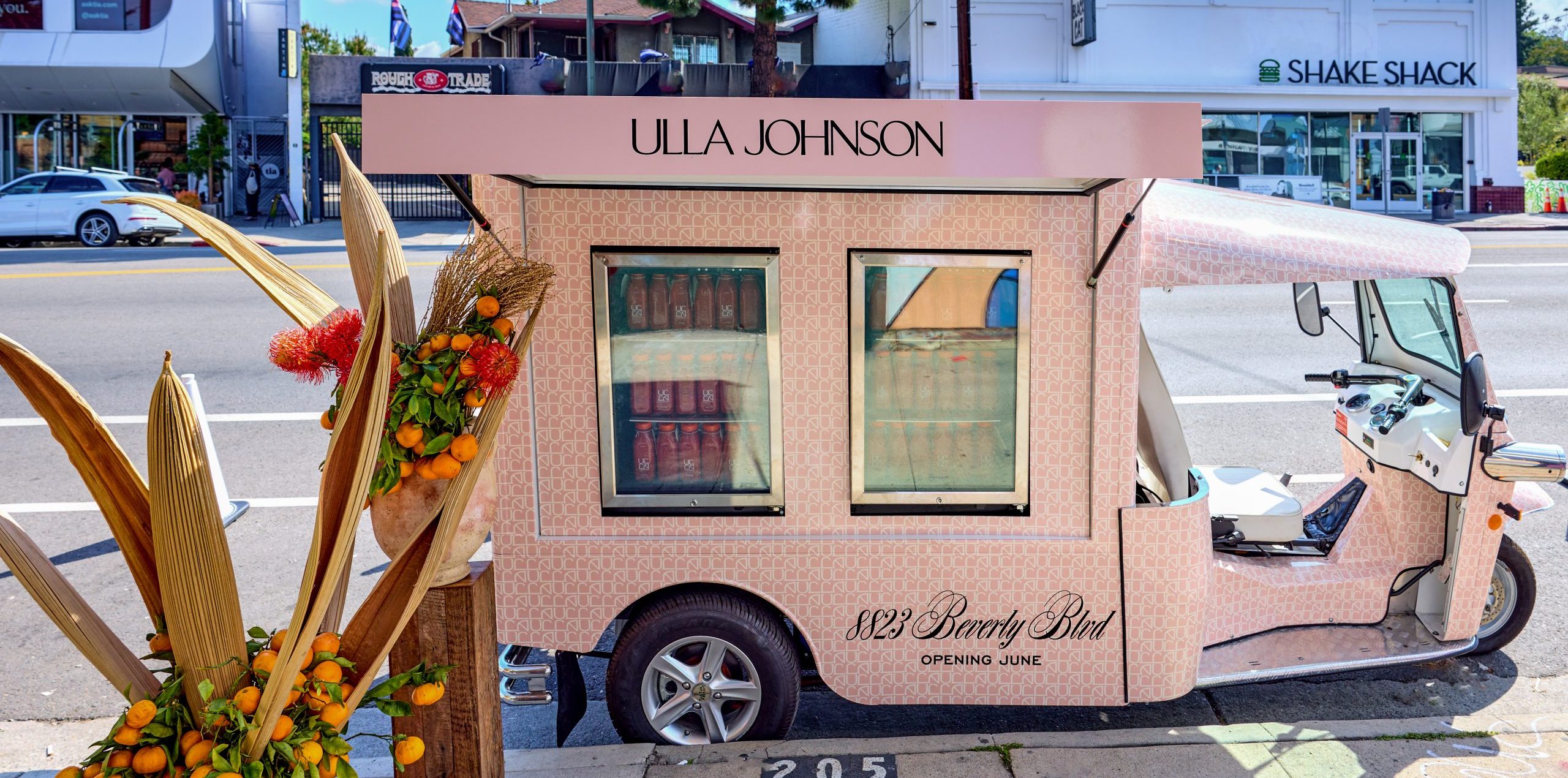 Ulla Johnson pink pop-up van parked by 8129 Beverly Blvd with orange flowers and branding nearby.