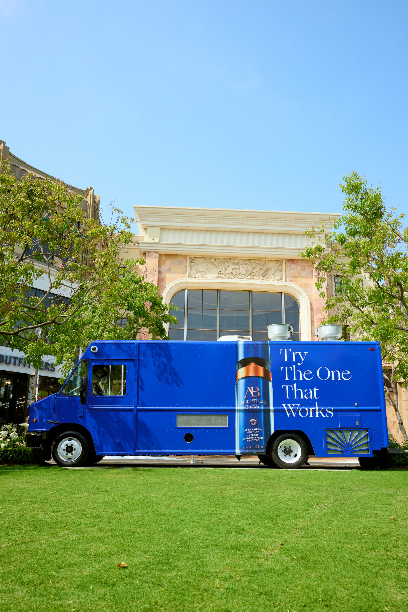 Augustinus Bader food truck with “Try The One That Works” parked on grass by a columned building.
