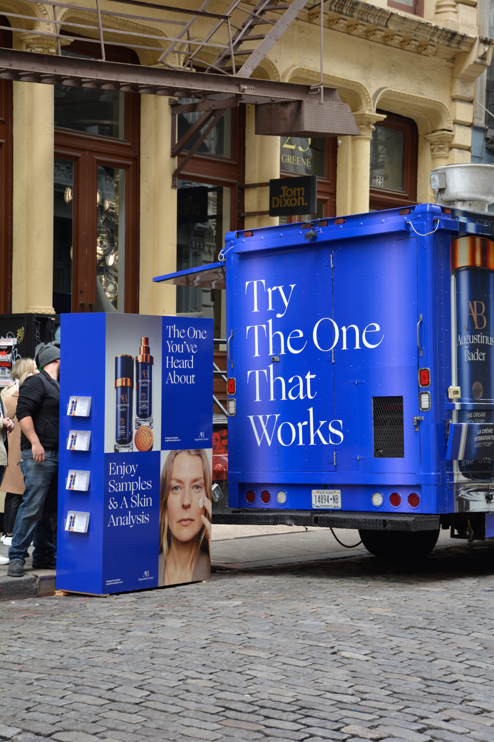 Blue truck and display promote Augustinus Bader skincare, offering samples and skin analysis.