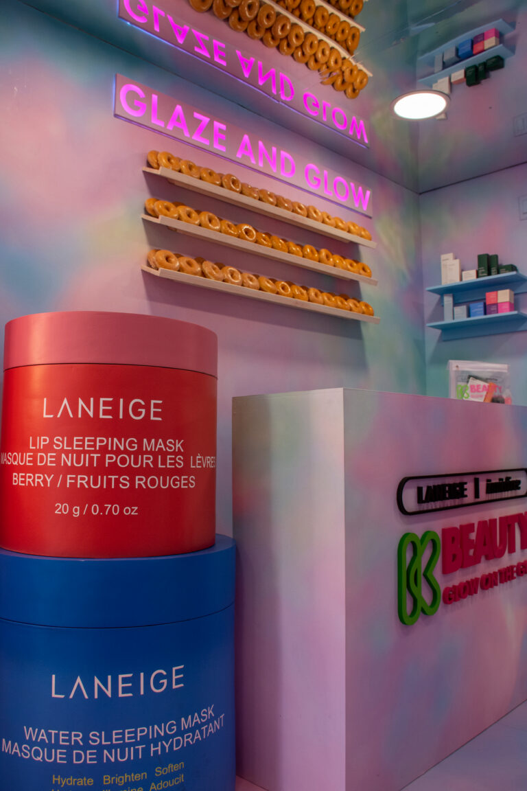 Store with "Glaze and Glow" neon sign, doughnut shelves, LANEIGE masks, and pink skincare counter.