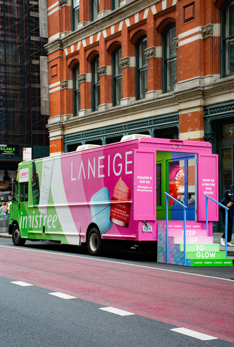 LANEIGE x innisfree skincare truck with product images and open doorway on city street.