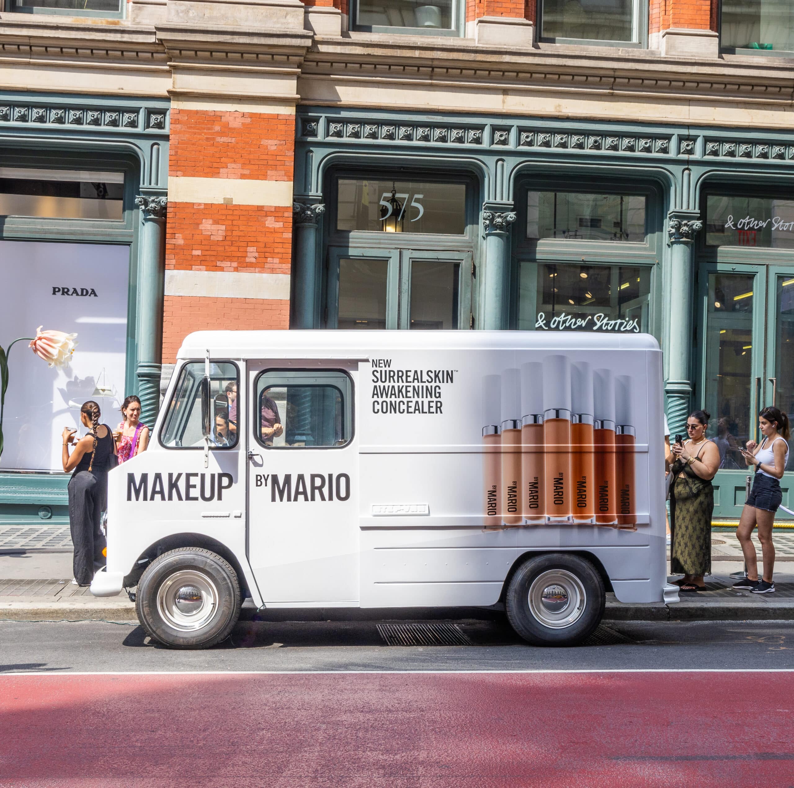 White Chevy P10 Makeup by Mario van with concealer ad parked on city street near shops.
