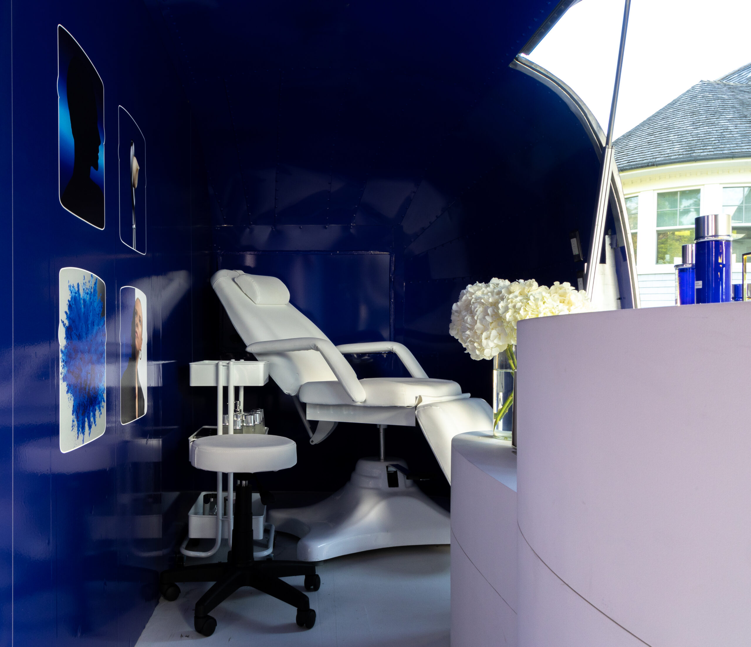 White reclining chair in blue-walled La Prairie pop up with spa equipment, products, and decor.