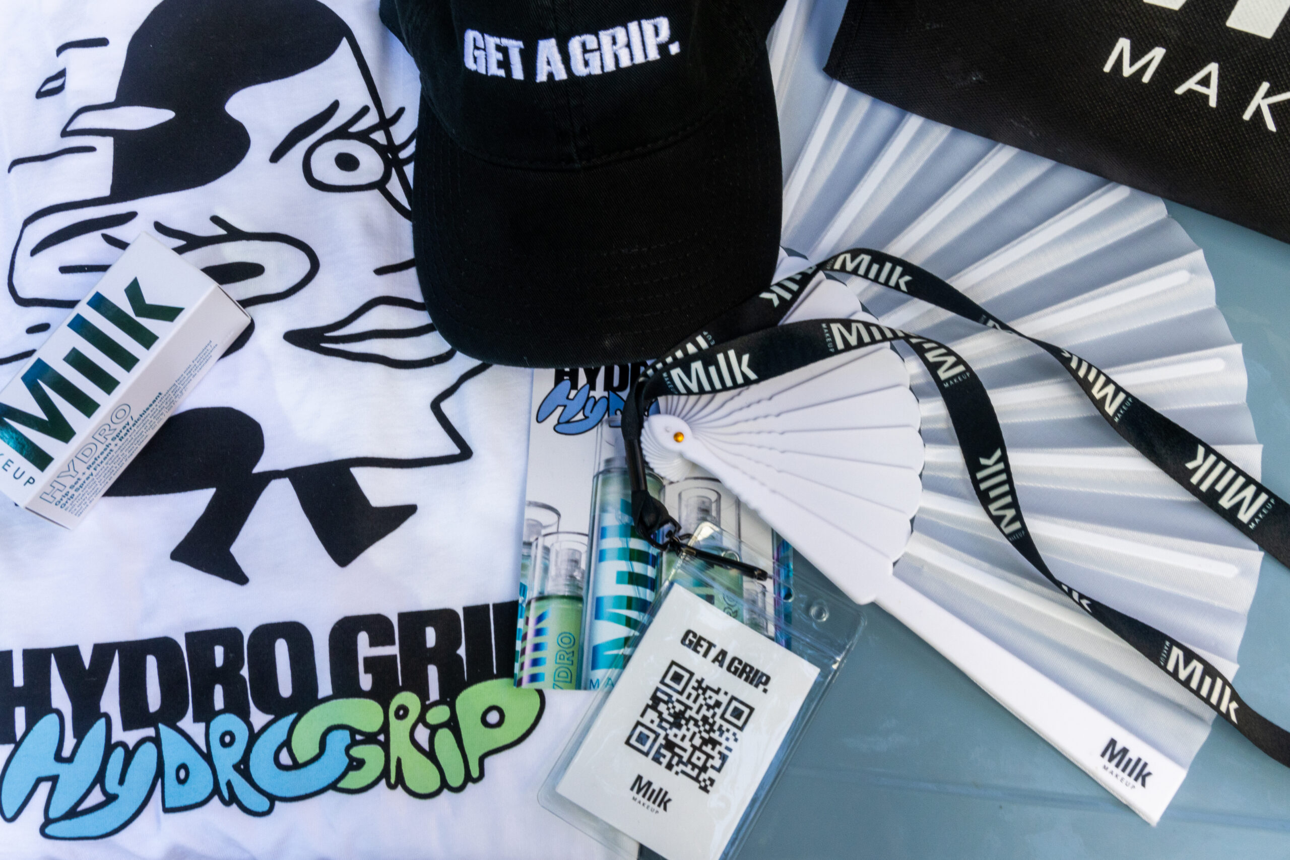 Milk Makeup items: HYDRO GRIP T-shirt, black cap, fan, tote bag, lanyards, lip balm, primers, badge.