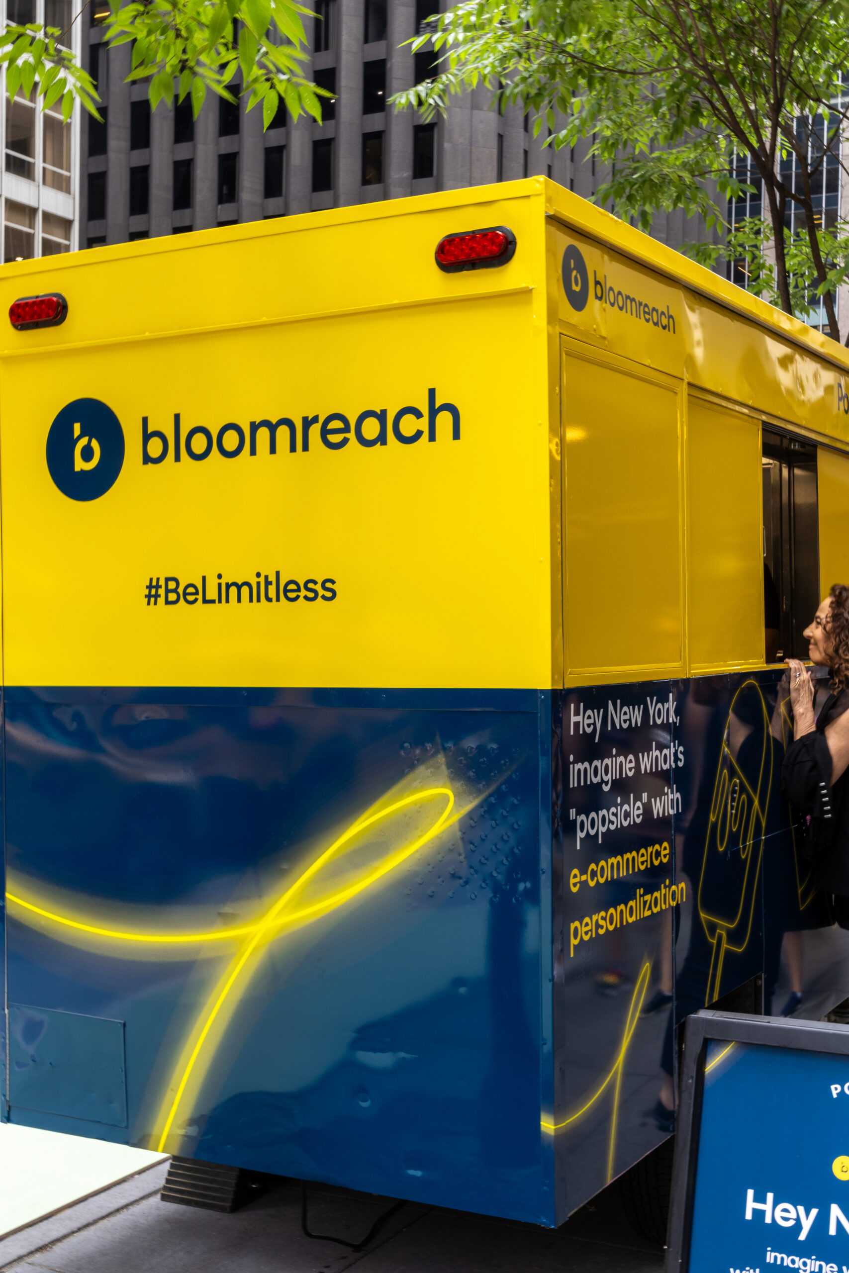 A yellow and blue Bloomreach truck is parked on a city street, promoting e-commerce personalization.