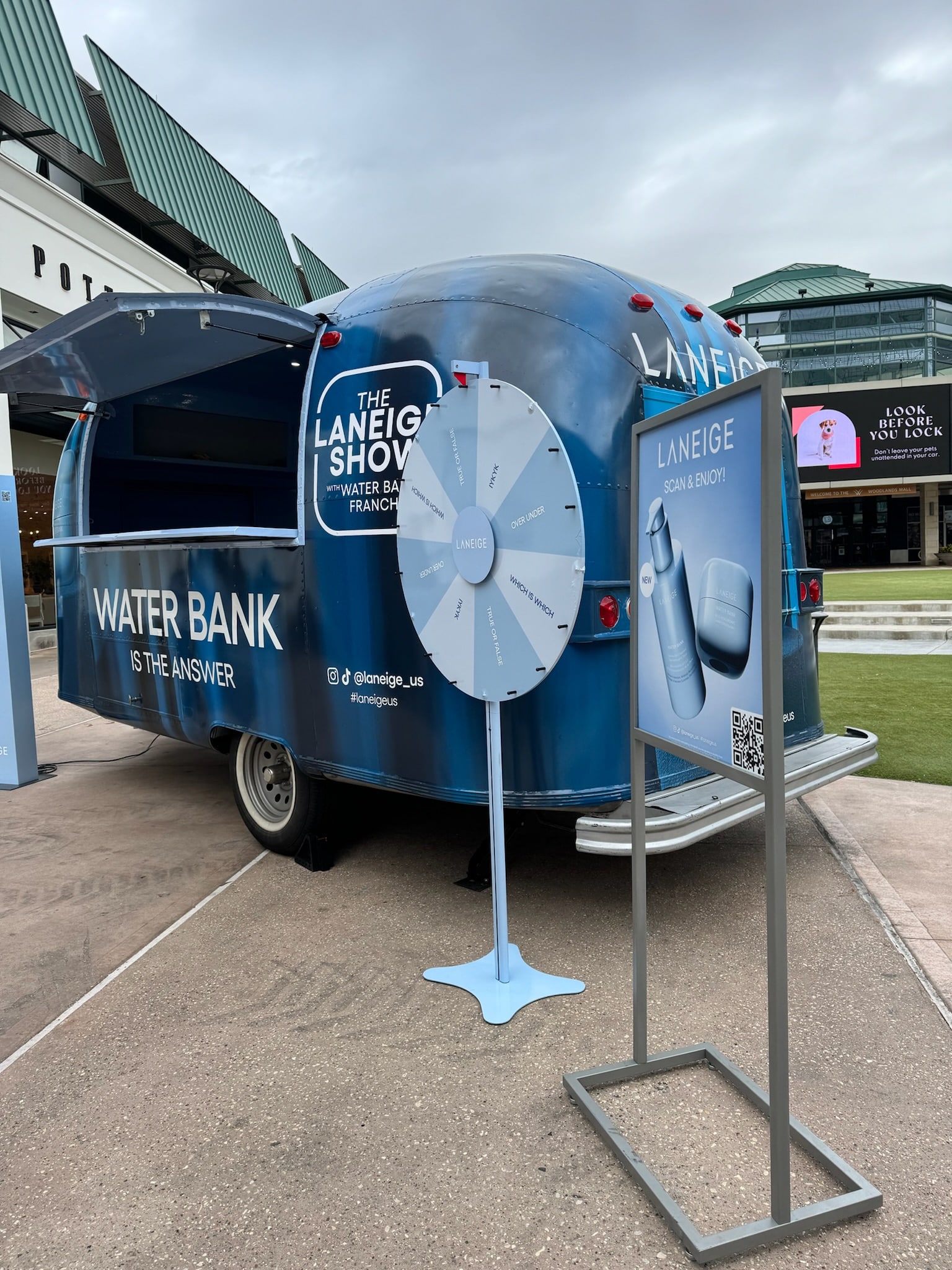 Blue Laneige trailer with Water Bank branding, prize wheel, sign with products and QR code outside.