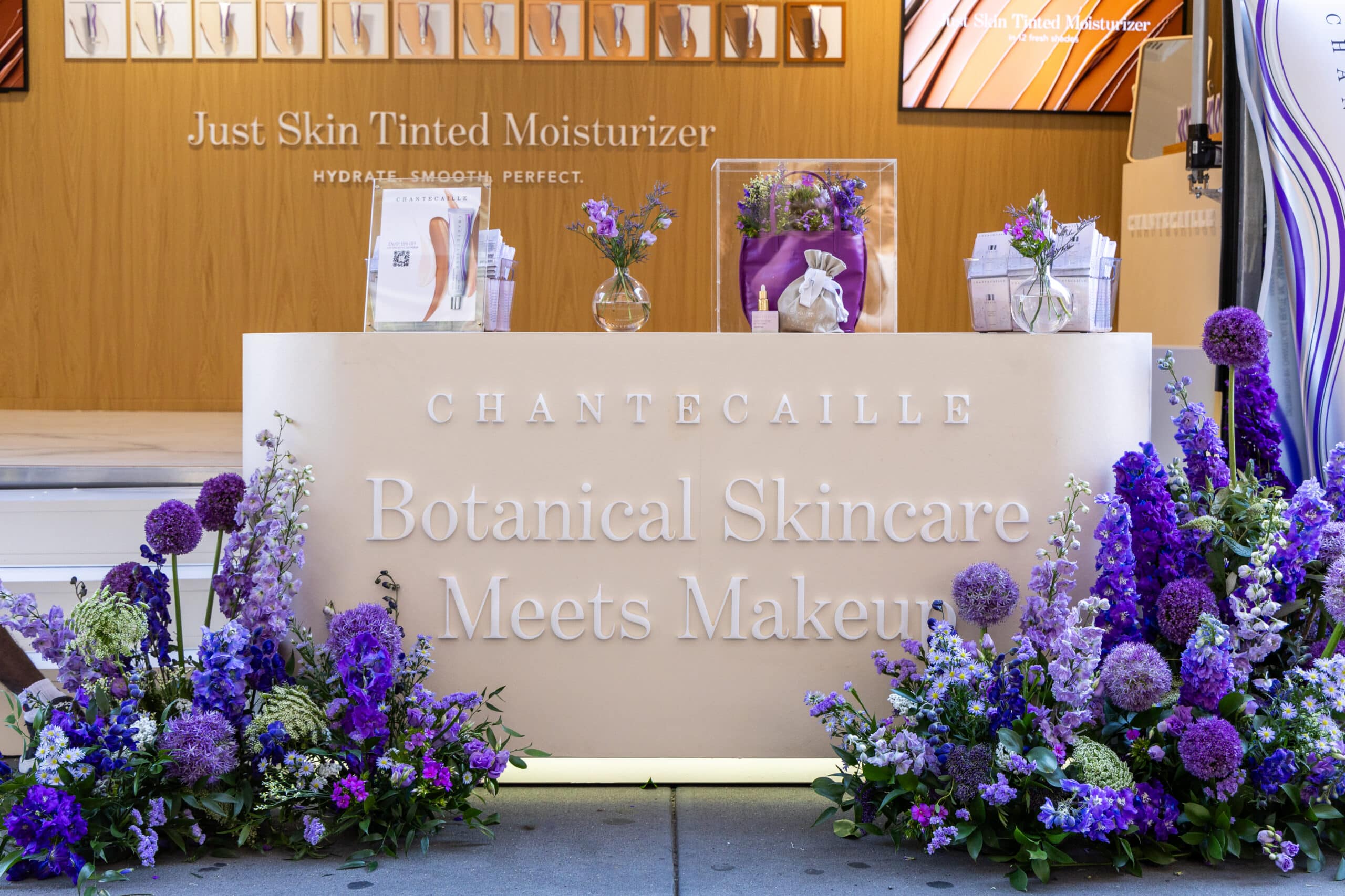 Chantecaille counter with purple flowers, vases, skincare products, and a skincare signage.