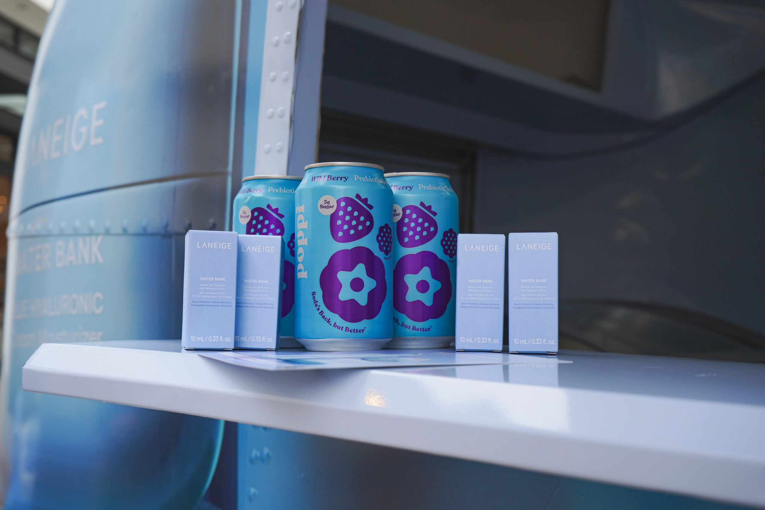 Three blue cans with berry designs and four blue Laneige boxes on a white shelf.