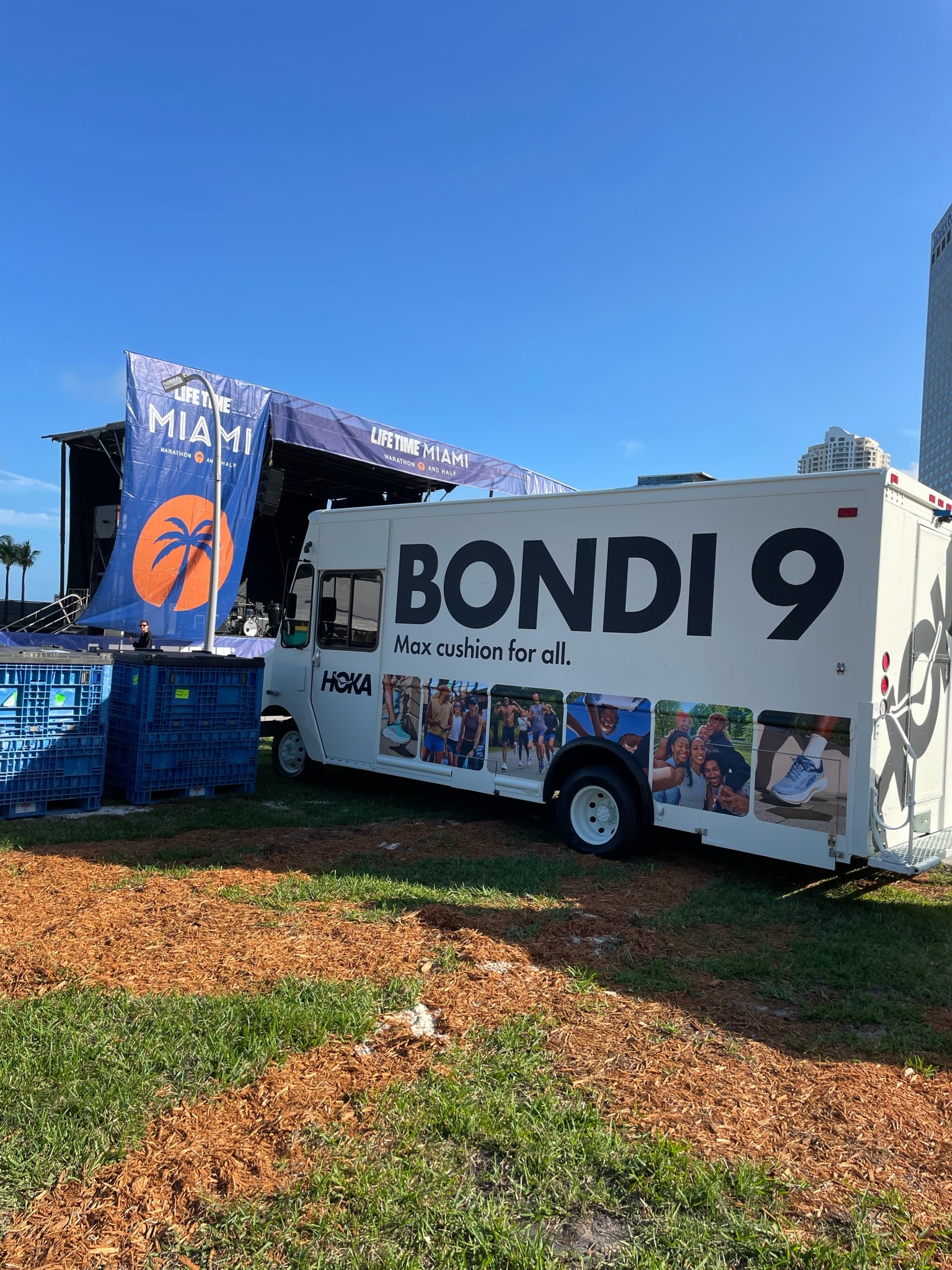 HOKA Bondi 9 truck with runner photos and “Max cushion for all” parked by a Life Time Miami stage.