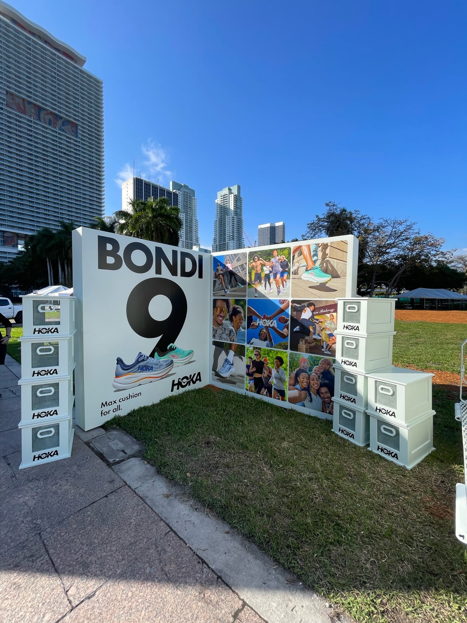 Hoka Bondi 9 outdoor display with large text, shoe images, people, boxes, and city buildings.