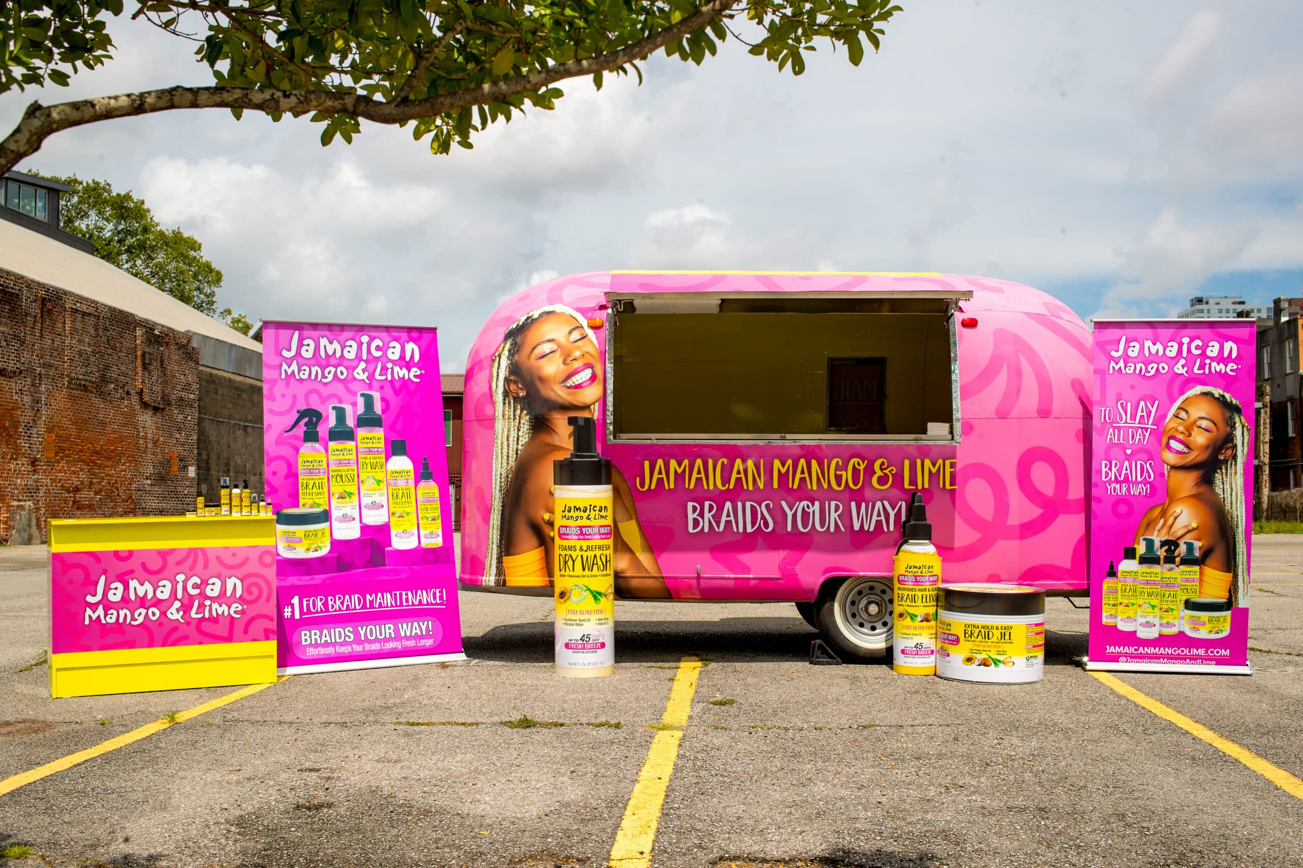 Pink Jamaican Mango & Lime trailer outdoors with banners, product displays, and hair care branding.