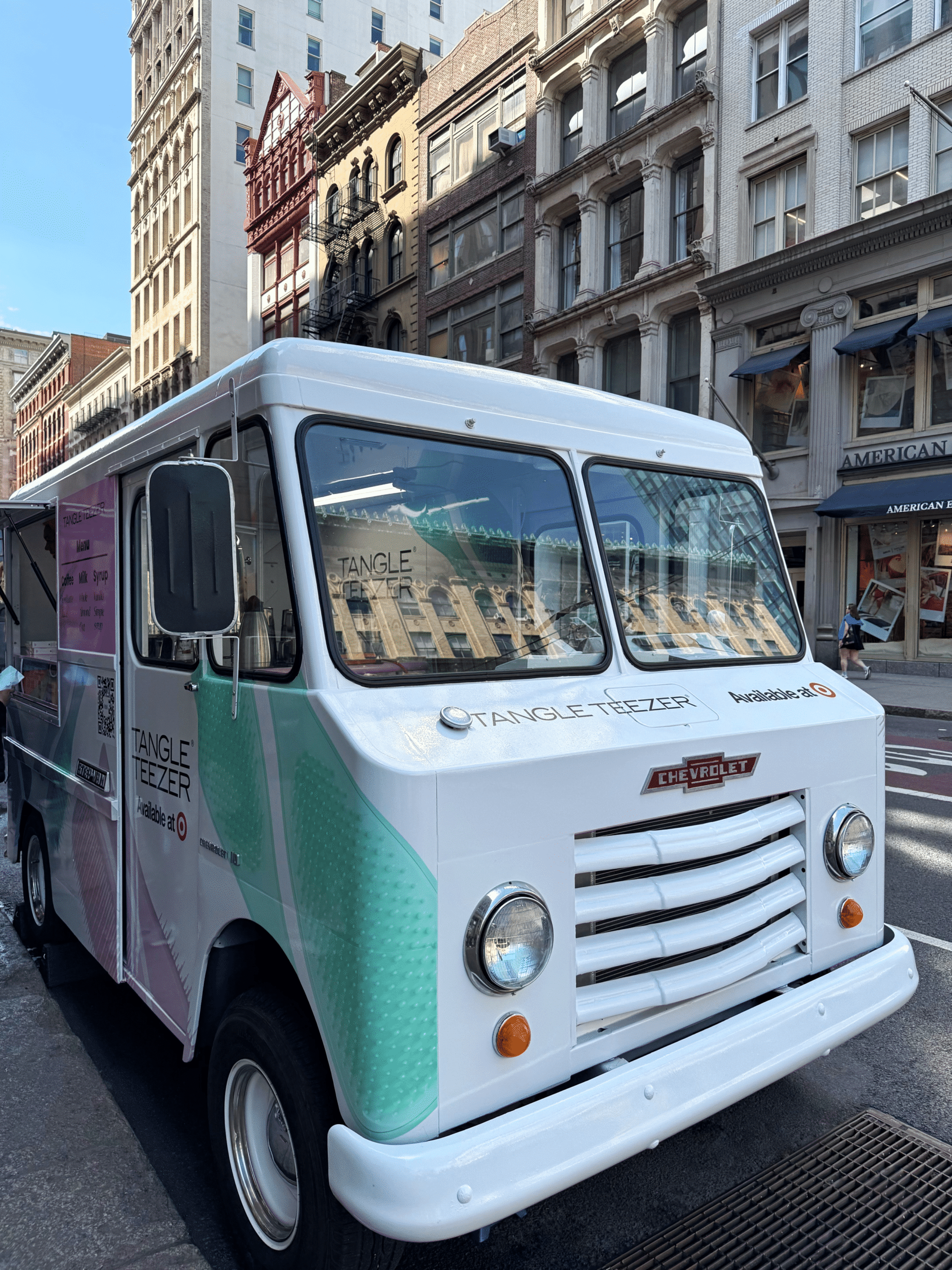 White Chevrolet food truck with Tangle Teezer and Sephora at 60 decals parked on city street.