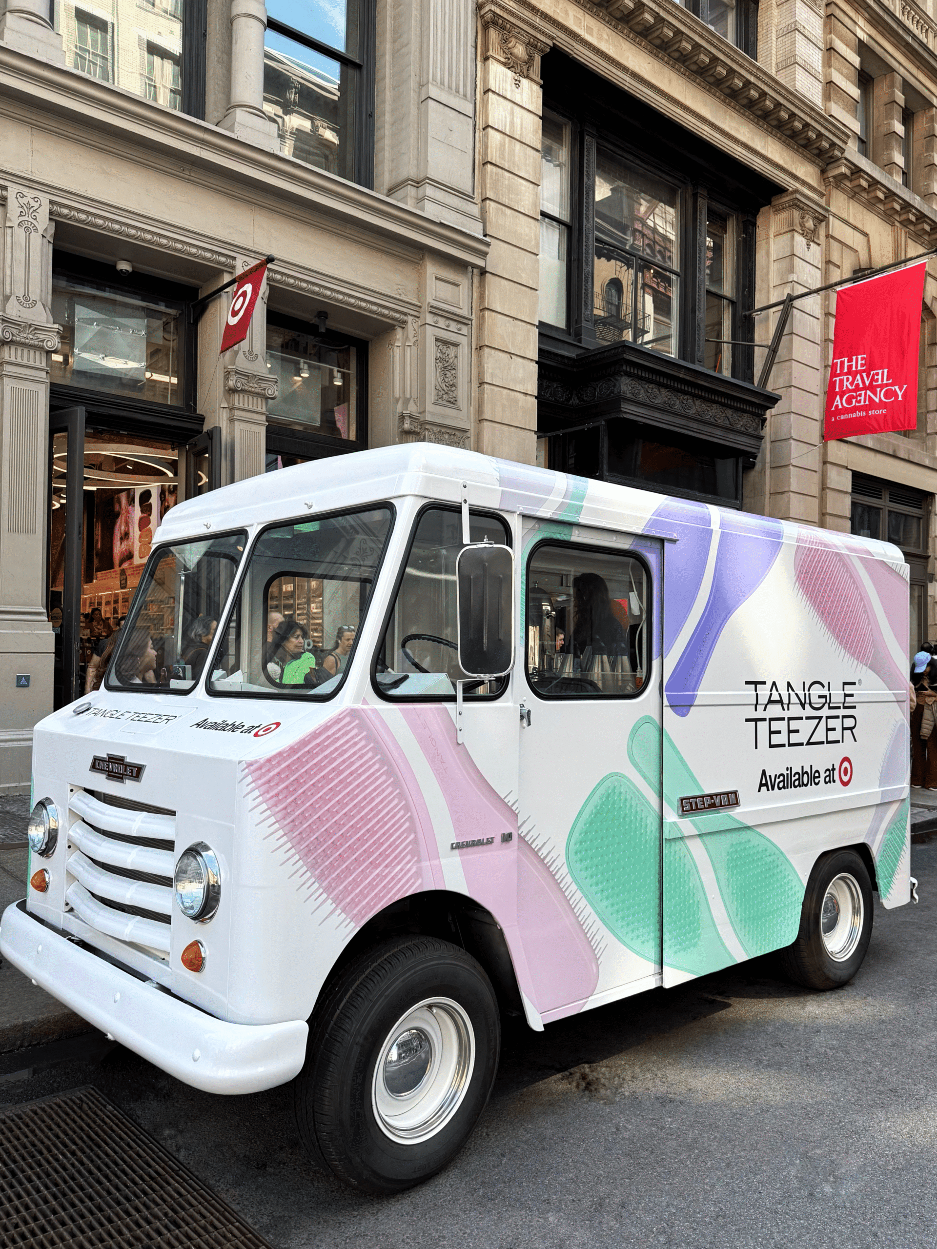 White van with Tangle Teezer branding and hairbrush graphics parked on a city street.