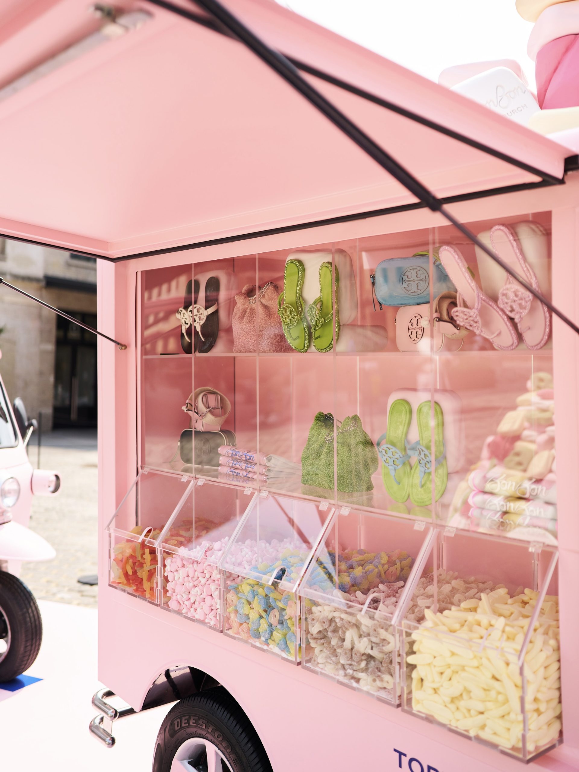 Pink cart with women’s accessories and shoes on top, candies in clear bins below.