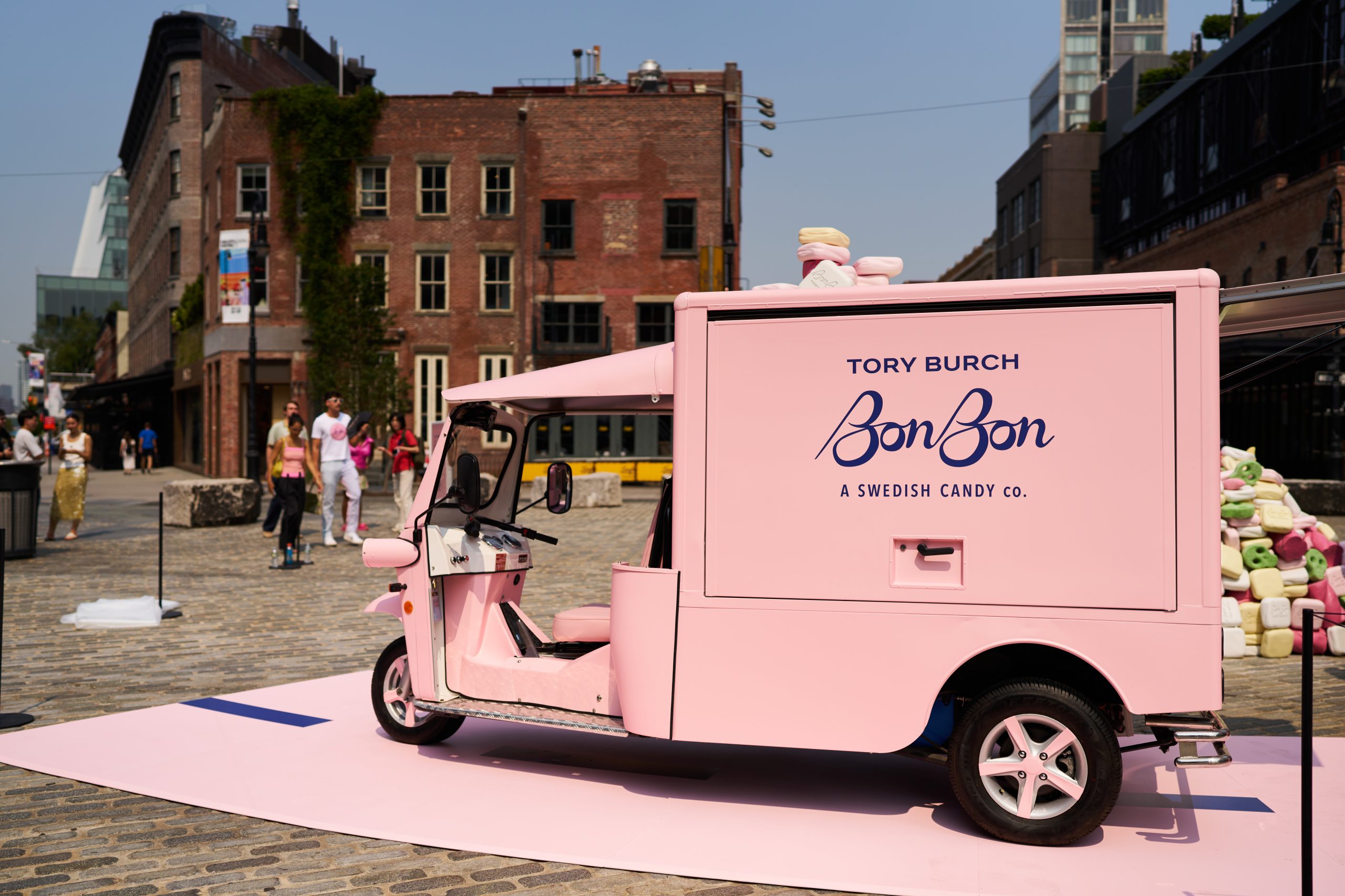 Pink Tory Burch BonBon Swedish Candy Co. food truck on cobblestone street with pastel candies.