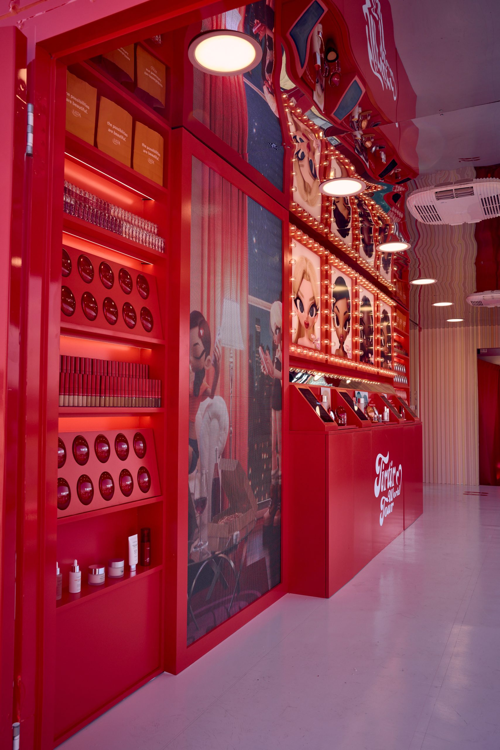 Red cosmetics store display with product shelves, animated wall art, mirrors, and bold signage.